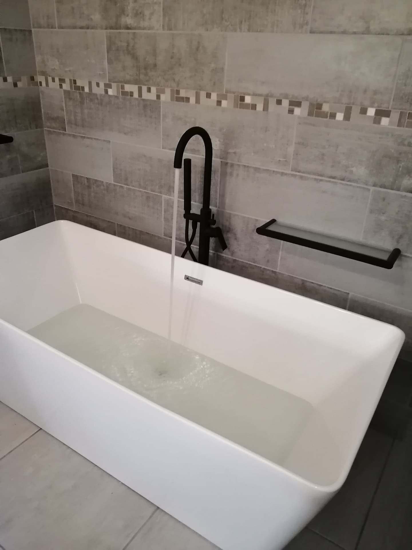 White freestanding bathtub with a black floor-mounted tap